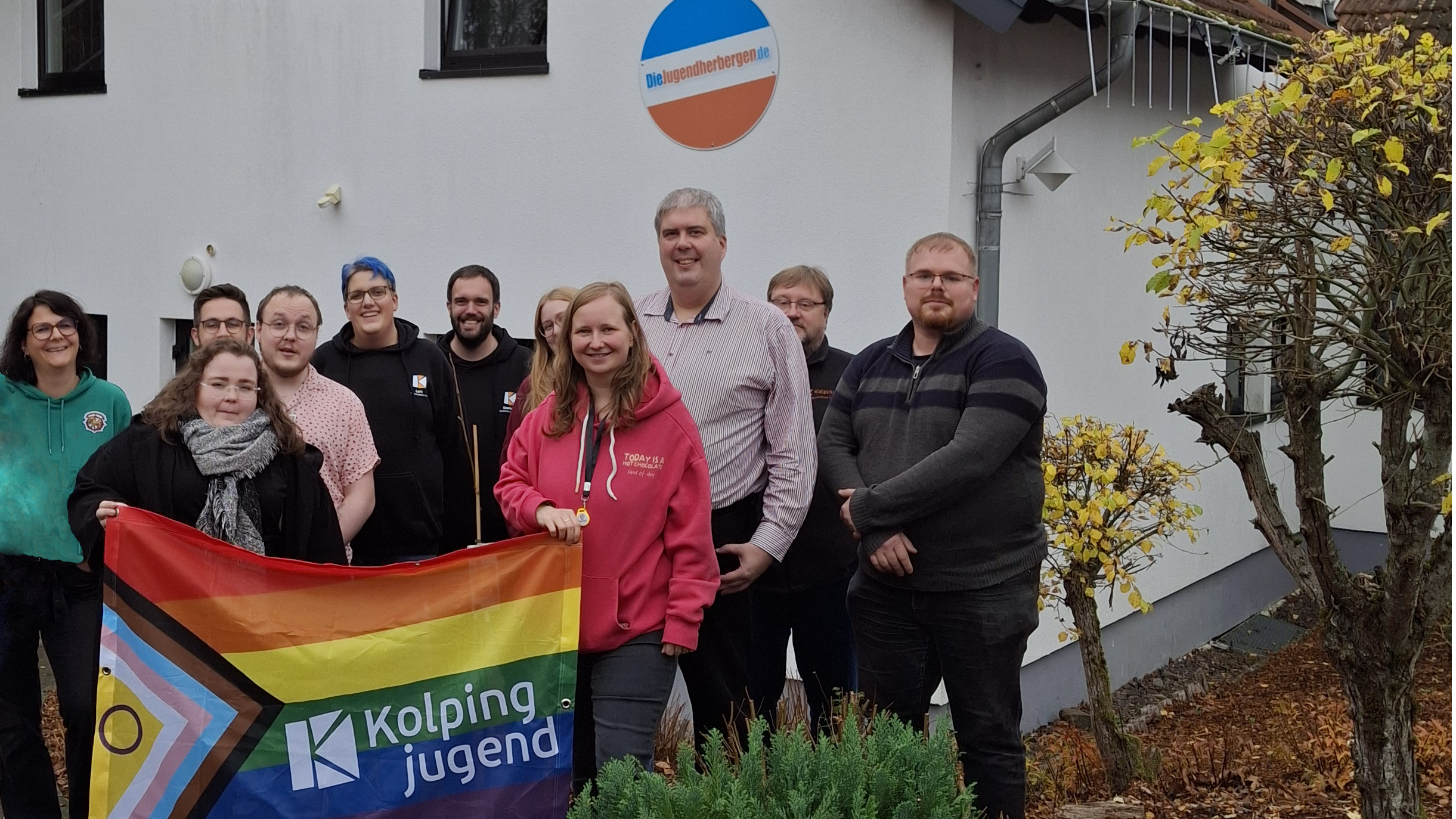 Teilnehmende der Diko vor der Jugendherberge in Tholey. Im Vordergrund halten Teilnehmende die Kolpingjugend Regenbogenfahne