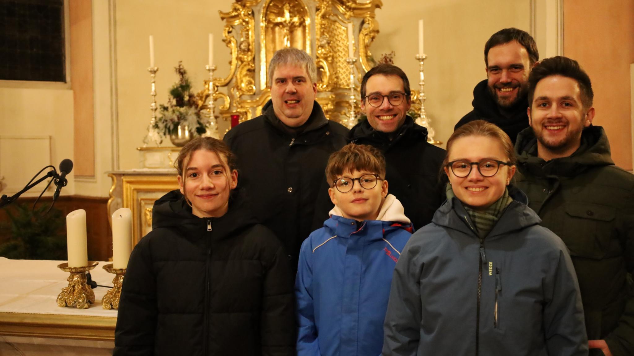 Teilnehmer des Gottesdienstes stehen vor dem Altarraum in der Kirche