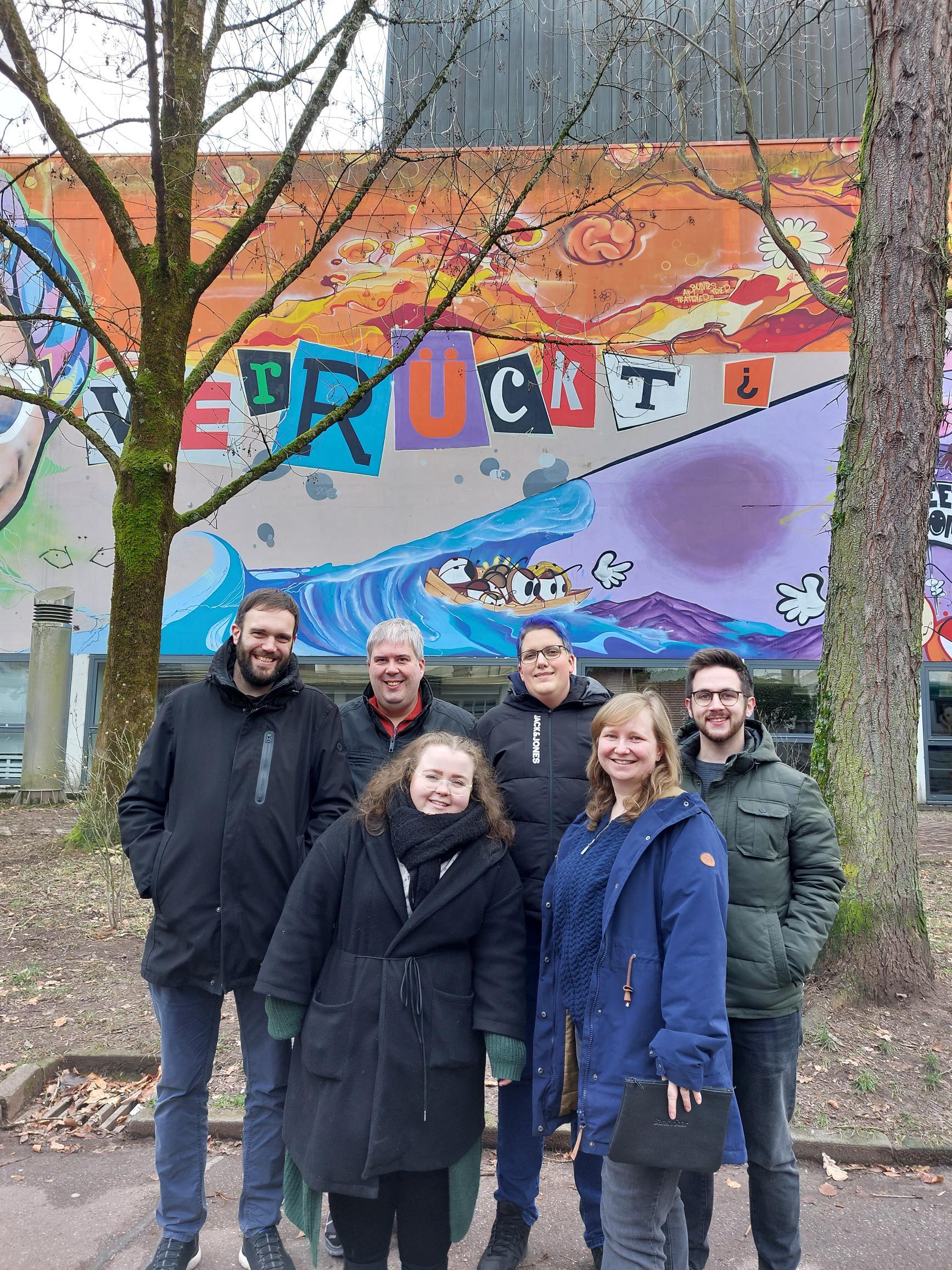 sechs Personen vor Graffiti Wand