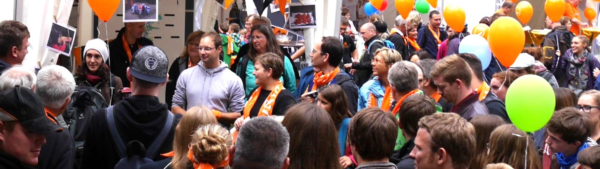 Man sieht eine Gruppe Menschen mit Kolpingschals und bunten Luftballons.