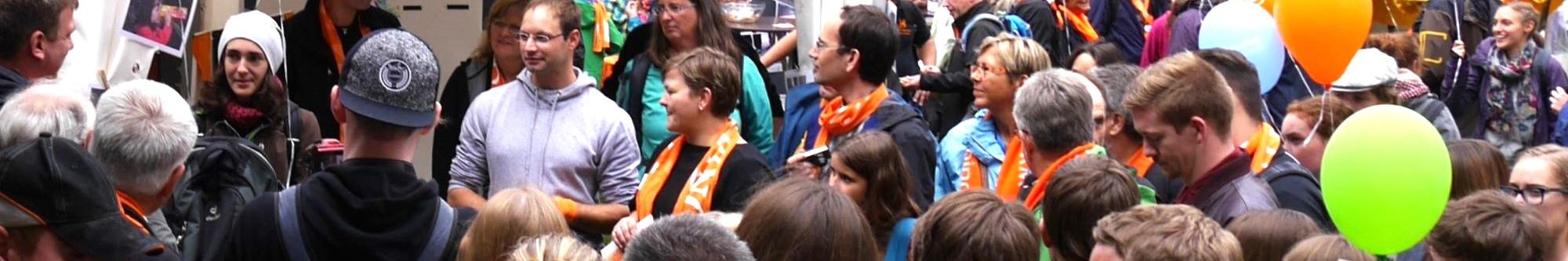 Man sieht eine Gruppe Menschen mit Kolpingschals und bunten Luftballons.