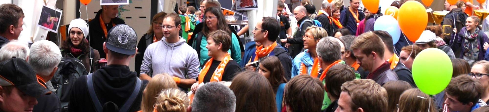 Man sieht eine Gruppe Menschen mit Kolpingschals und bunten Luftballons.